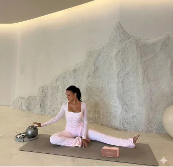 Kvinde på yogamåtte i et lyst rum med en rosa Lumina-højtaler ved siden af